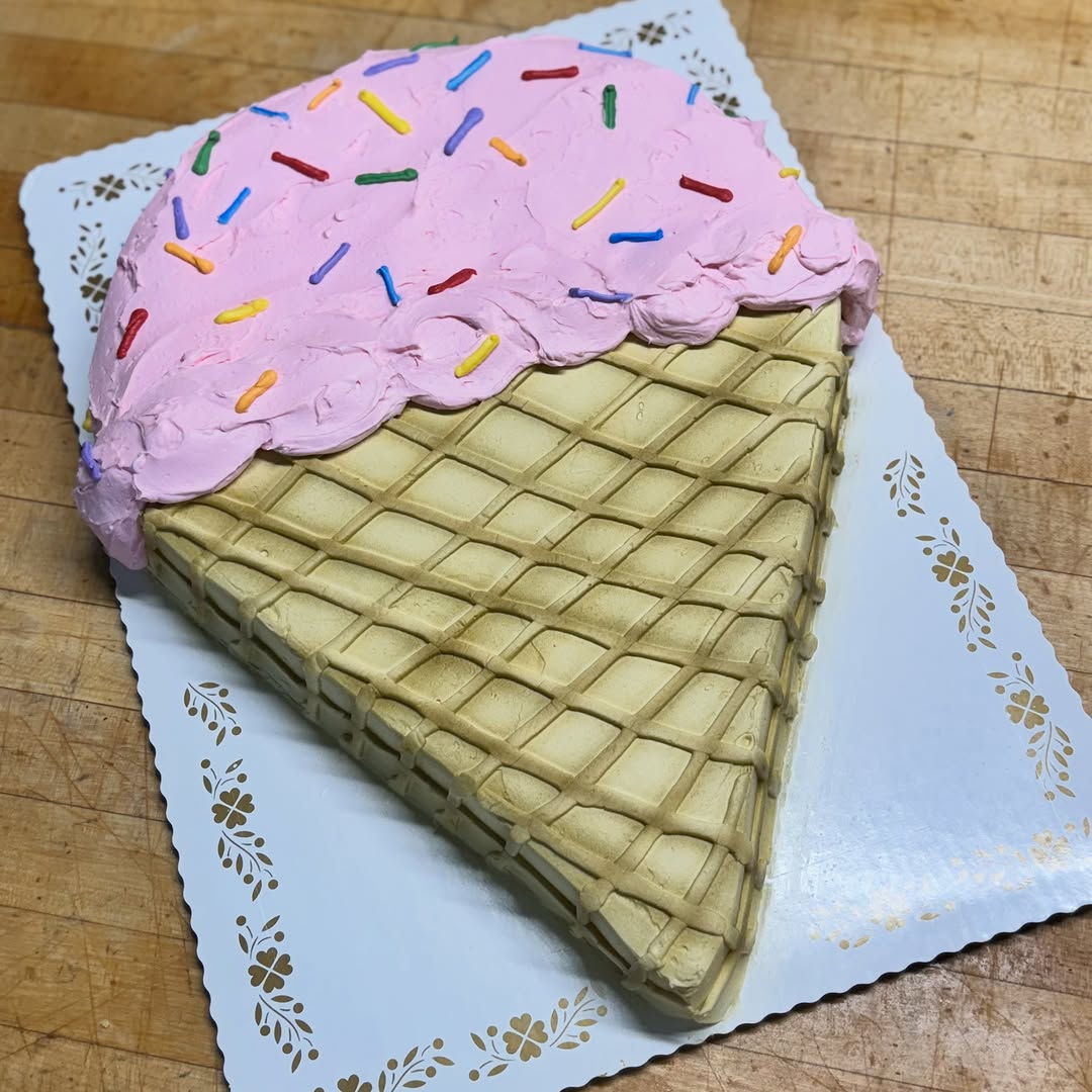 Cake shaped like an ice cream cone with pink icing and sprinkles