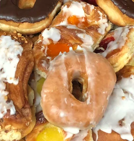 Glazed donut on a tray of Danish and filled donuts