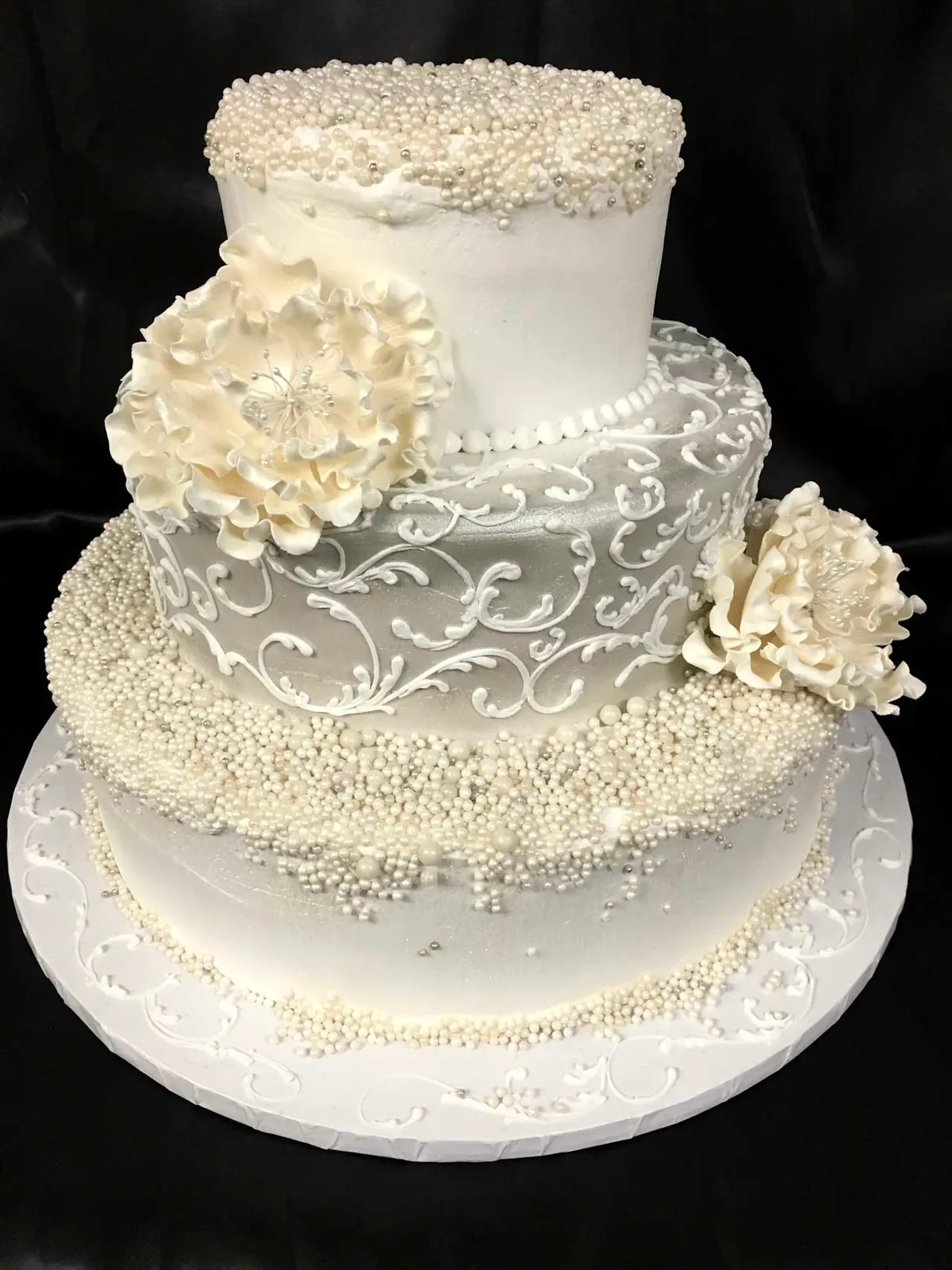 Ivory three-tier wedding cake with pearl beading and sugar flowers